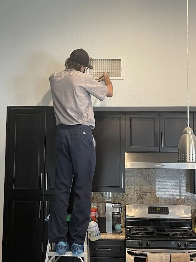 Technician inspecting an air vent during HVAC service in Midland